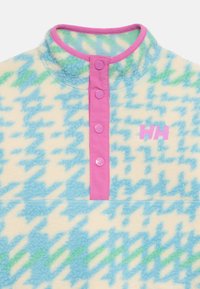 Fleecepullover med en krämfärgad bas och blå-grön hundtandmönster, med en rosa tryckknappsöppning och logotyp på bröstet.