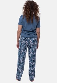 Blaues Baumwoll-T-Shirt kombiniert mit locker sitzenden, gemusterten Schlafanzughosen mit floralem Design in Blau- und Weißtönen.