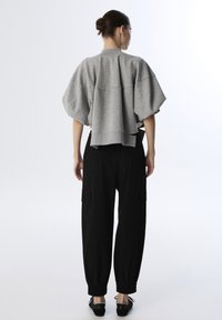 Grijze oversized sweatshirt met verlaagde schouders, een cropped achterkant en een geribbelde zoom, gecombineerd met zwarte taperende cargobroek met zijzakken.