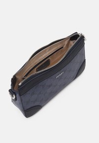 Sac à main bleu marine avec un motif texturé, fermeture éclair argentée et intérieur beige. Comprend une étiquette de marque et des accents en cuir.
