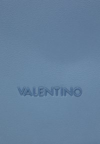 Ljusblått texturerat lädermaterial med präglad "VALENTINO"-logotyp i fet stil. Ytan verkar slät med subtila kornmönster.