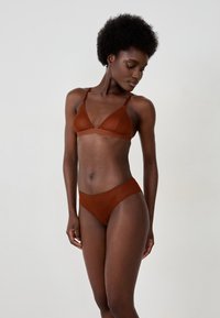Braunes Netz-Lingerie-Set mit einem Triangel-Bralette mit verstellbaren Trägern und passendem hochgeschnittenen Slip. Glatte Textur und zarte Verzierungen.