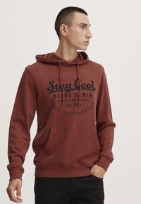 Felpa color bordeaux con cappuccio regolabile, tasca frontale e testo stampato in nero. Presenta polsini e orlo a coste per un look aderente.