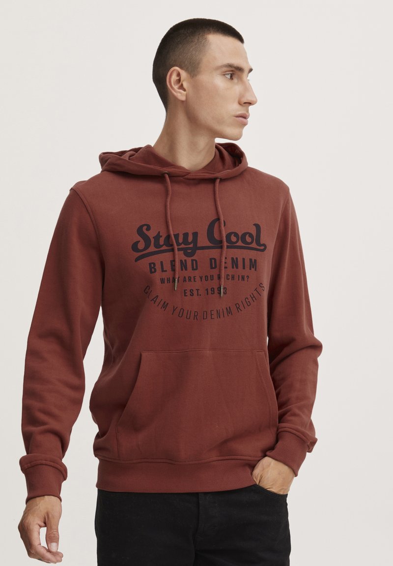 Felpa color bordeaux con cappuccio regolabile, tasca frontale e testo stampato in nero. Presenta polsini e orlo a coste per un look aderente.