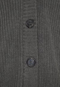 Grey knitted cardigan featuring a textured pattern and three black buttons along the front. The fabric displays a ribbed structure.