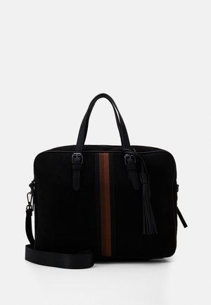 Sort ruskinds taske med to bæreremmes, aftagelig skulderrem og en brun lodret stribe. Har en dekorativ kvast på siden.