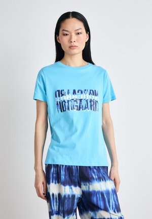 Light blue cotton t-shirt with "morcsaadr" text in multicolored, blurred lettering. Features short sleeves and a round neckline.