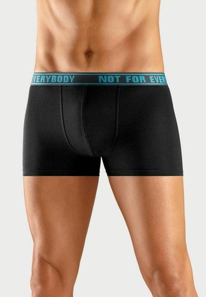 Schwarze Boxershorts aus weichem Stoff, mit einem breiten türkisfarbenen Bund, auf dem der Text "NICHT FÜR JEDEN" steht. Eng anliegendes Design.