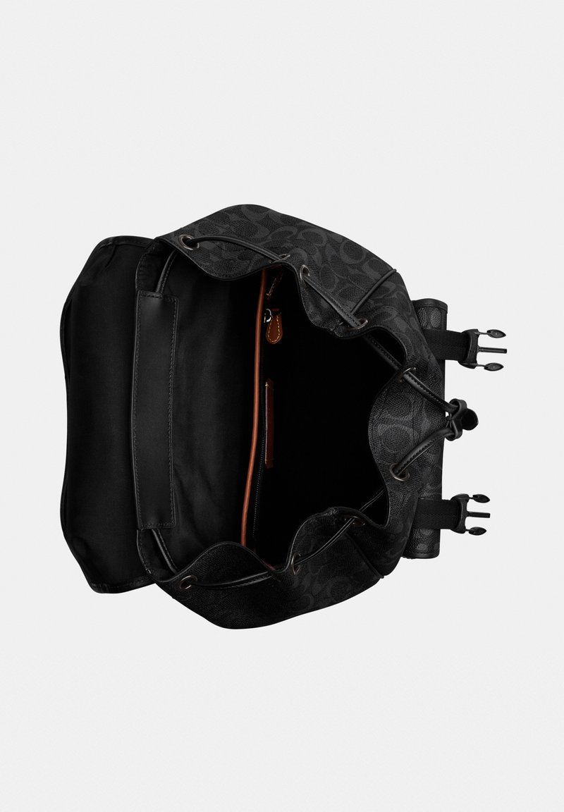 Mochila negra con estampado y cordón, abierta para mostrar un compartimento principal espacioso con bolsillo interior con cremallera y correas ajustables con hebillas.