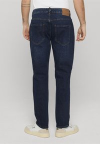 Tmavě modré džíny z denimu s přímým střihem nohavic, vybavené dvěma zadními kapsami a koženou nášivkou na pásku.