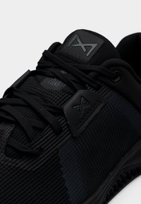 Pantof sportiv negru cu partea superioară sintetică texturată cu accente tonale, sistem de șireturi elaborat și talpă din cauciuc.