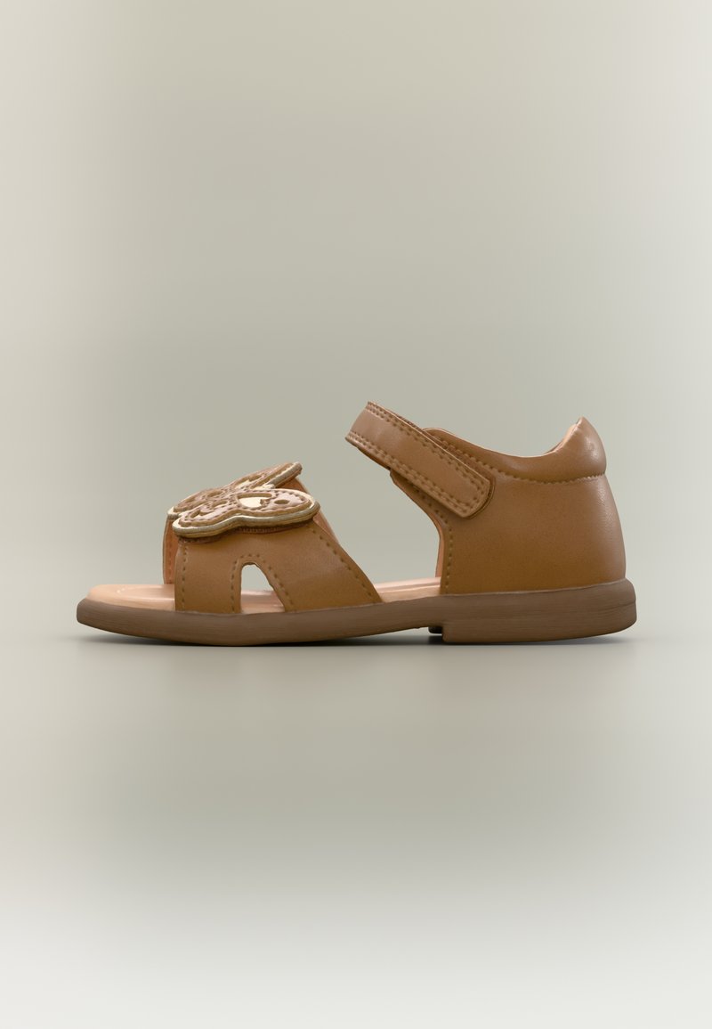 Καφέ παιδικό σανδάλι από λείο συνθετικό υλικό. Διαθέτει ανοιχτή μύτη, διακοσμητική λεπτομέρεια πεταλούδας και ρυθμιζόμενο ιμάντα με βέλκρο.