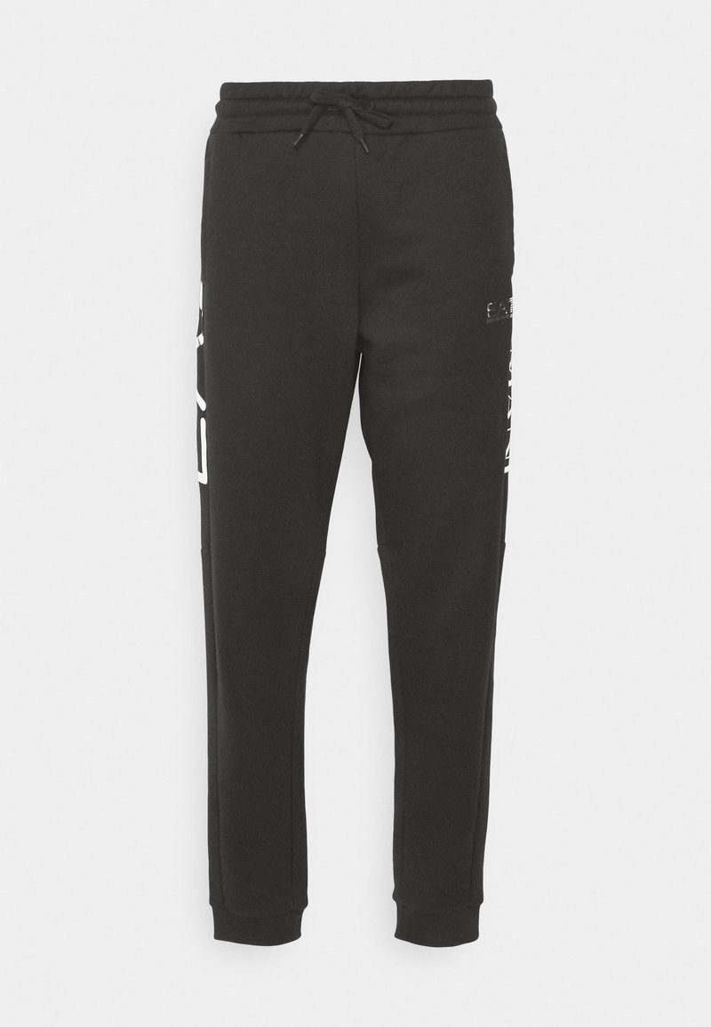 Pantalones de chándal negros hechos de tela suave, con cintura ajustable, bolsillos laterales y una marca blanca en la pierna izquierda.