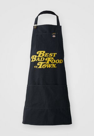 Tablier en toile noir avec du texte jaune indiquant "La meilleure mauvaise nourriture en ville", avec une poche avant et une sangle de cou réglable.