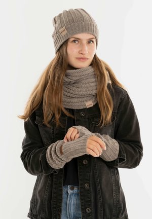 Grauer gestrickter Beanie, Schal und fingerlose Handschuhe. Texturiertes Design mit Rippstrick. Schal um den Hals gewickelt, Handschuhe zeigen die Hände.