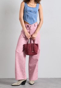 Denim avkortad topp med fyrkantig halsringning, rosa vida byxor, en liten handväska i burgunderröd mocka och beige spetsiga ankelstövlar med klack.