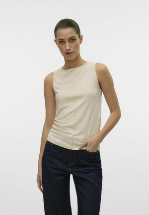 Haut sans manches beige avec un col rond et un détail de couture verticale, associé à un jean en denim foncé. Tissu lisse, design ajusté.