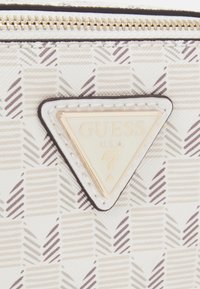 Bijela teksturirana tkanina s geometrijskim uzorkom u nijansama sive. Ima zlatni trokutasti logo i zlatni zatvarač na zips.