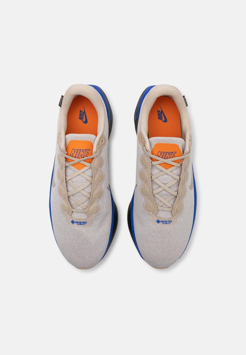 Zapatillas de deporte beige de corte bajo con detalles en azul y plantillas naranjas, que cuentan con una parte superior de malla, marca GORE-TEX y un sistema de cordones circular.
