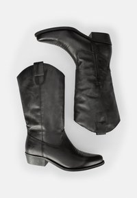 Botas de vaquero de cuero negro con puntera puntiaguda, un tacón de altura media, cremalleras en los lados interiores y costuras decorativas en el caña.