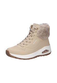 Zapatilla alta beige con cuello de piel sintética, suela de goma texturizada, diseño con cordones y almohadilla de aire visible en la zona del talón.