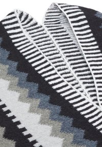Fular tricotat multicolor cu modele geometrice în culori negre, albe și nuanțe de gri. Textură moale, cu un design în zig-zag și dungi.