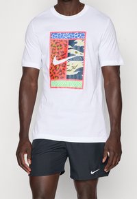 Camiseta blanca de algodón con un diseño gráfico colorido que representa estampados de animales y formas abstractas en rojo, azul, verde y amarillo.