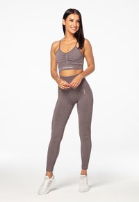 Top corto atlético gris con fruncidos en el frente, combinado con leggings de tiro alto. Ambos están hechos de un material elástico y texturizado.