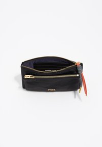 Bolsita de piel negra con cremalleras doradas, una de ellas presenta un acento rojo y gris. El interior tiene múltiples ranuras para tarjetas y una textura suave.