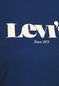 Tissu bleu avec un grand texte blanc "Levi's" et un texte plus petit en dessous indiquant "Since 1873" sur un vêtement.