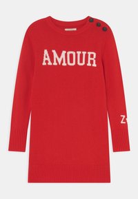 Czerwona dzianinowa sukienka z napisem "AMOUR" na białym tle, okrągły dekolt i detal z guzikami na ramionach. Rybaczki przy mankietach i u dołu sukienki nadają fakturę.
