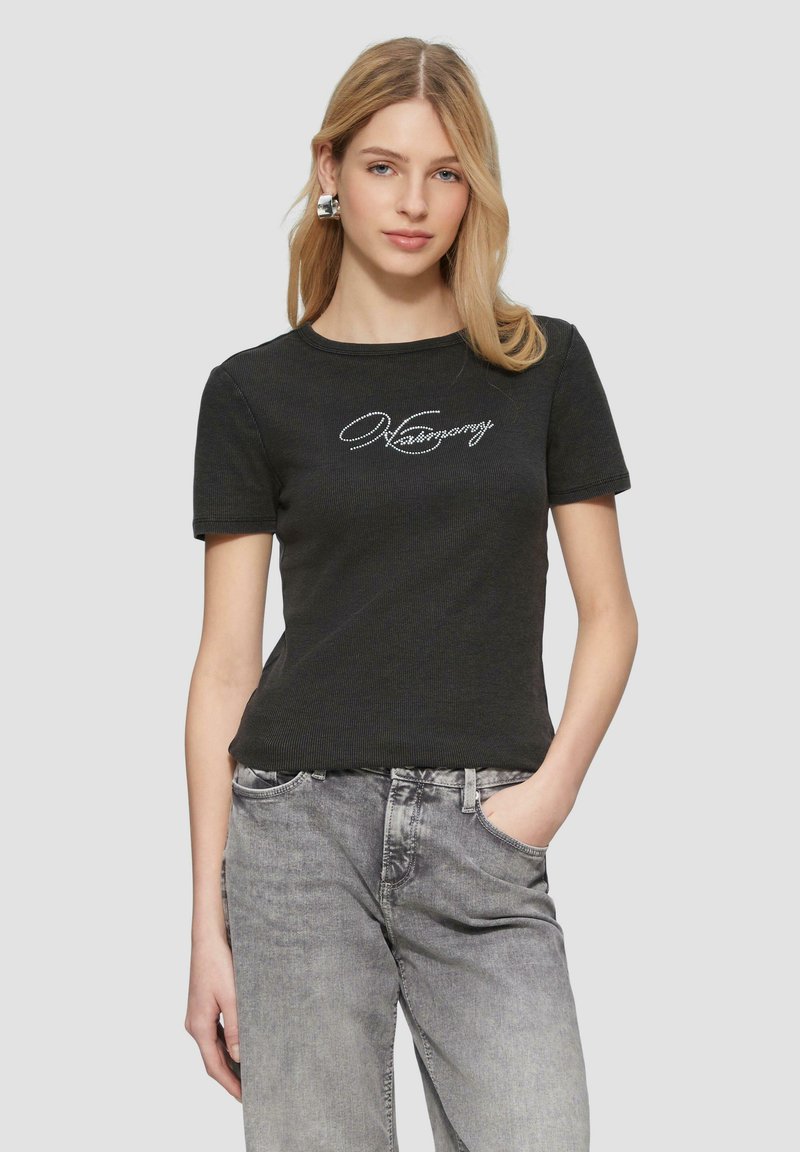 Schwarzes, geripptes T-Shirt mit kurzen Ärmeln und rundem Halsausschnitt, mit weißem Textlogo über der Brust, kombiniert mit hellgrauen Jeans.