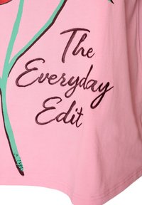 Tissu rose avec un motif graphique vert et marron foncé et un texte en italique indiquant "The Everyday Edit" sur le côté droit.