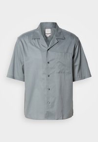 Camisa de botones de manga corta en tejido gris claro con una textura suave, que presenta un bolsillo en el pecho y un diseño de cuello clásico.