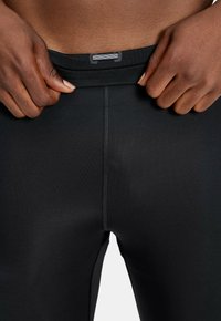 Sorte atletiske leggings lavet af et glat, strækbart stof. Har en høj talje og en søm foran for et tætsiddende look.