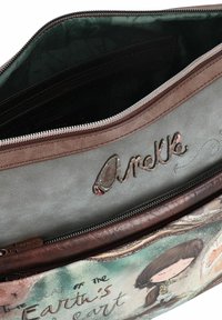 Brązowa torebka z sztucznej skóry z zamknięciem na zamek. Wnętrze posiada zieloną podszewkę. Charakteryzuje się wytłoczonym tekstem i ilustracją postaci.