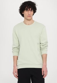 Felpa verde chiaro con maniche lunghe, colletto a giro e dettagli in rilievo sul logo davanti, realizzata in un morbido misto cotone.
