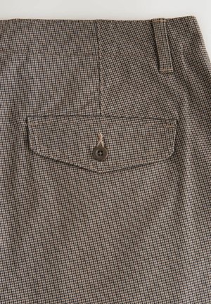 Brun og tan ternet stof med en baglomme, der har en enkelt brun knap, forstærkede syninger og en glat overflade.