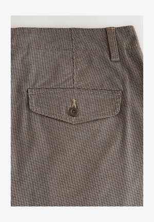 Brun og tan ternet stof med en baglomme, der har en enkelt brun knap, forstærkede syninger og en glat overflade.