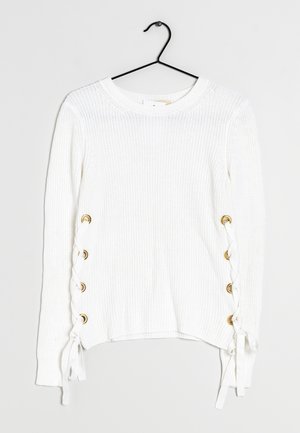 Jersey blanco de punto con escote redondo, ojales dorados en los laterales y detalle de cordones blancos en el dobladillo.