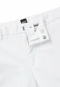 Vita bomullbyxor med dragkedja, knappstängning och BOSS-logotag. Har en ren design och mjuk textur.
