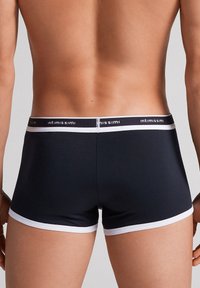 Svarta kalsonger i boxerstil med vit kant, med en elastisk midja med "intimissimi"-logotyp och en åtsittande passform som är designad för komfort.