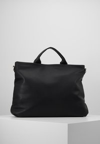 Černá kožená taška přes rameno s texturovaným povrchem, zaoblenými rukojeťmi a prostorným obdélníkovým tvarem. Jednoduchý design bez vnějších kovových prvků.