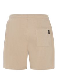 Beige puuvillashortsit, joissa on joustava vyötärö, takatasku ja siisti helma, suunniteltu mukavuutta ja rentoa käyttöä varten.