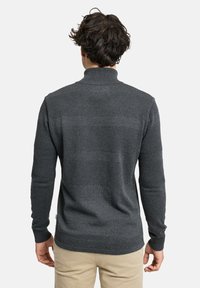 Tummanharmaa neulepusero, jossa on korkea kaulus, tekstuuriset kuviot ja ribbitetty pääntie. Takakuvassa näkyy vaakasuuntainen raitakuvio.