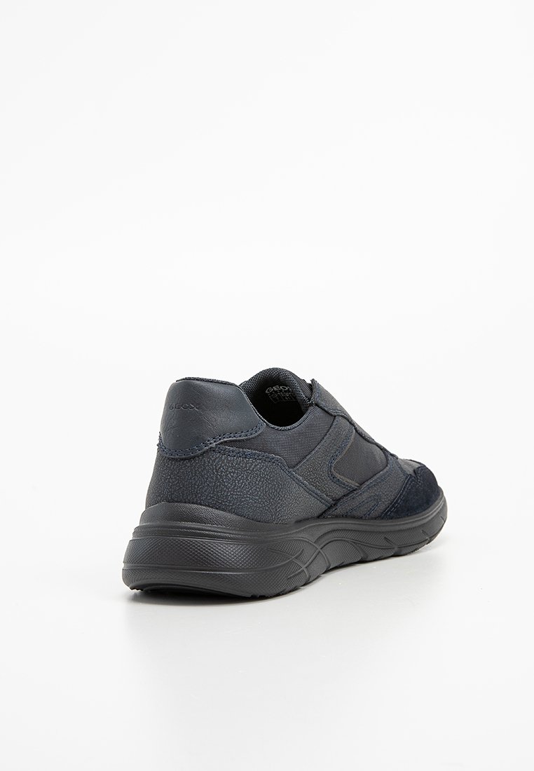 Sneaker blu scuro caratterizzato da una combinazione di pelle testurizzata e tessuto, design curvo, suola ammortizzata e stile minimalista.