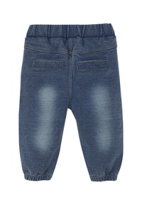 Denimbyxor med elastisk midja, med två bakfickor och en urtvättad blå nyans med elastiska mudd vid anklarna.