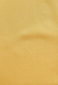 Kankaan kudos, joka on tasaisen sinappikeltaista, ja siinä on sileä, kudottu rakenne, jossa on hienovarainen kiilto ja tasainen kuitumalli.