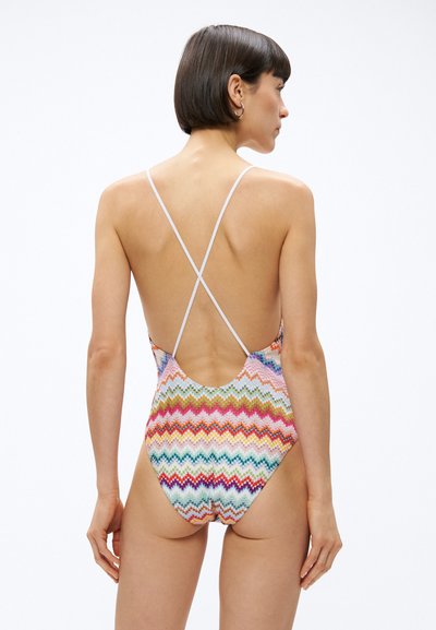 Jednoczęściowy kostium kąpielowy z wzorem zygzaków w różnych kolorach, z niskim dekoltem na plecach i cienkimi, krzyżującymi się ramiączkami. Gładka, elastyczna tkanina.