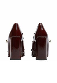 Scarpe con tacco alto in vernice bordeaux con tacco spesso, punta a punta e dettaglio in metallo dorato sul retro, con una texture liscia.